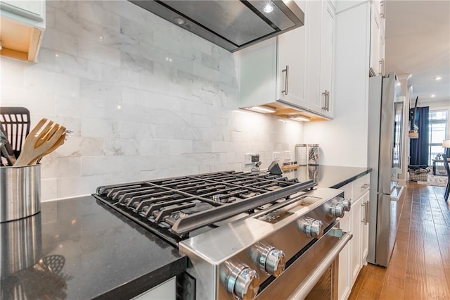 1964 Attell Way, Decatur, GA 30033 - kitchen with appliances with stainless steel finishes, white cabinets, wall chimney exhaust hood, backsplash, and light wood-style flooring