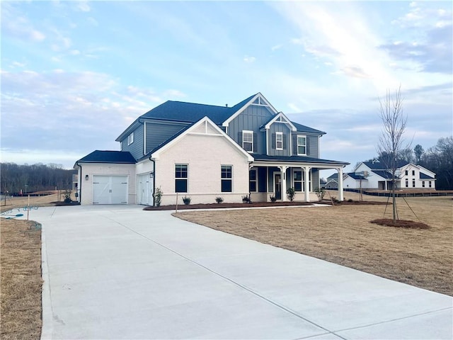 view of front of house featuring a front yard, covered porch, concrete driveway, a garage, and board and batten siding