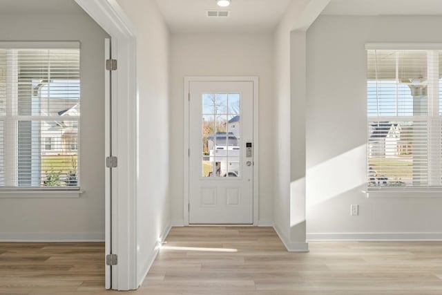 doorway with light wood-style flooring, baseboards, and visible vents