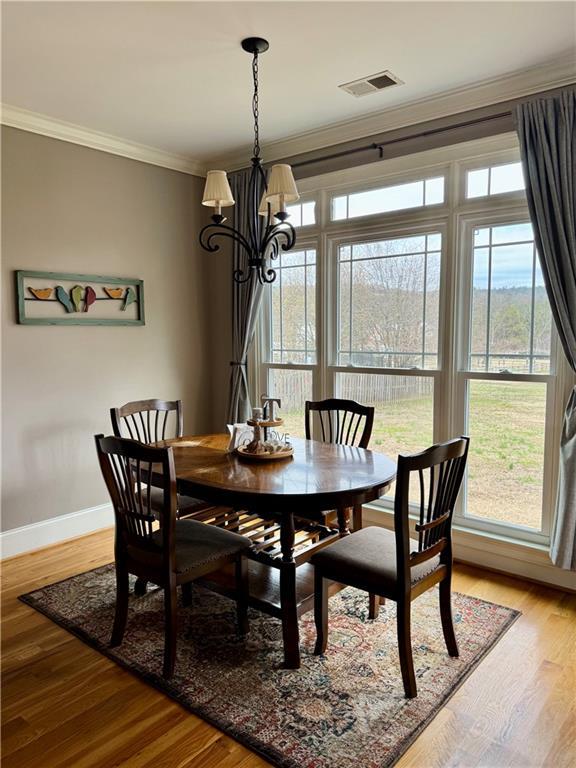 living room featuring visible vents, ornamental molding, a stone fireplace, wood finished floors, and high vaulted ceiling