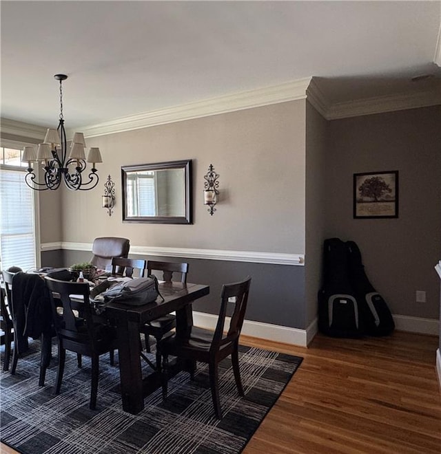 dining area with an inviting chandelier, wood finished floors, baseboards, and ornamental molding