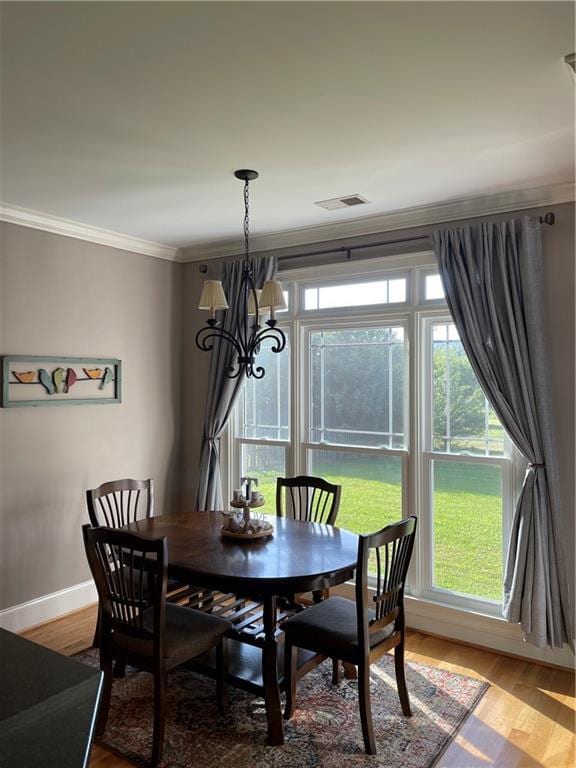 dining space with ornamental molding, an inviting chandelier, baseboards, and wood finished floors