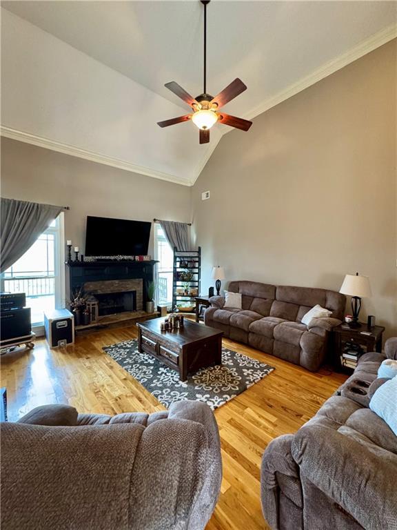 living area with a ceiling fan, wood finished floors, and high vaulted ceiling