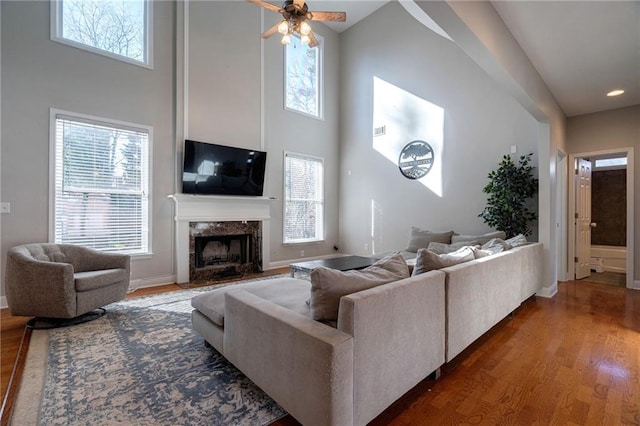 living room with plenty of natural light, dark hardwood / wood-style flooring, a premium fireplace, and a high ceiling