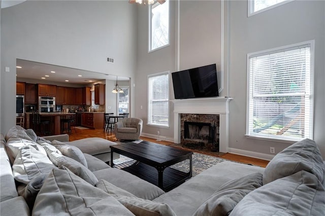 living room featuring a notable chandelier, light hardwood / wood-style floors, and a premium fireplace