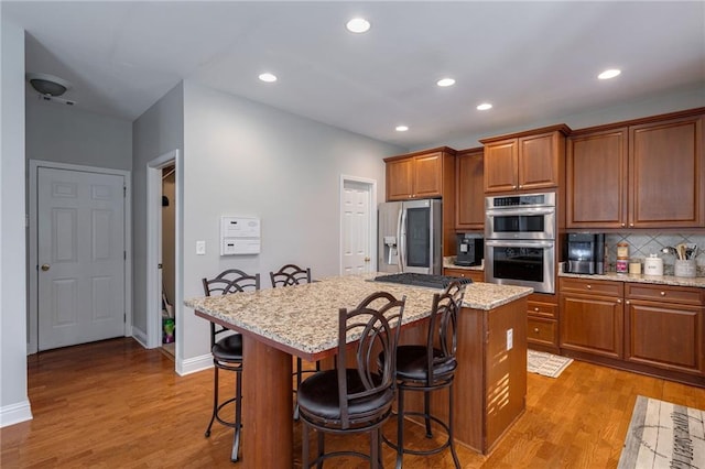 kitchen featuring light stone countertops, appliances with stainless steel finishes, a breakfast bar, and a kitchen island