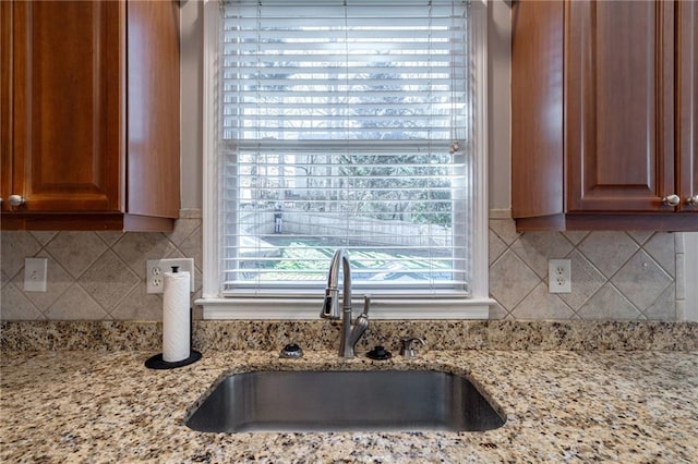 kitchen featuring sink, backsplash, and light stone counters