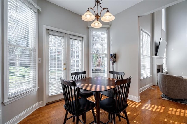 dining area featuring french doors, a notable chandelier, and light wood-type flooring