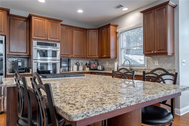 kitchen featuring stainless steel appliances, light stone countertops, a center island, and a breakfast bar