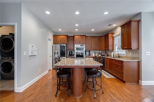 kitchen with sink, stainless steel appliances, light stone countertops, and a kitchen island