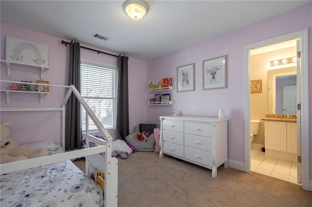 bedroom featuring light colored carpet and ensuite bathroom