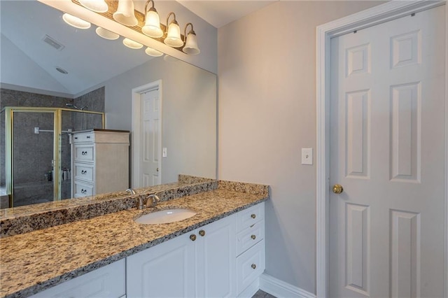 bathroom featuring vanity, vaulted ceiling, and a shower with door