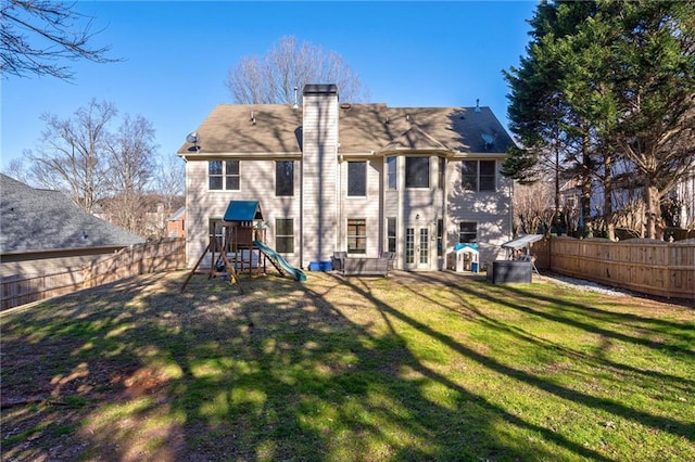 back of property featuring a lawn and a playground