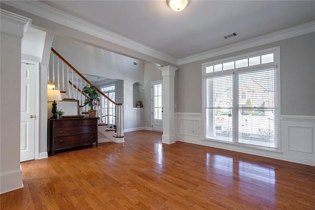 foyer entrance featuring hardwood / wood-style floors, ornamental molding, and ornate columns