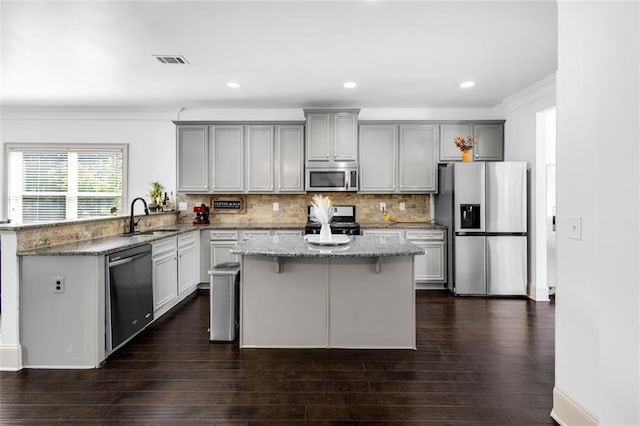 908 Rainsong Ct, Braselton, GA 30517 - kitchen featuring stainless steel appliances, gray cabinetry, ornamental molding, light stone countertops, and a kitchen island