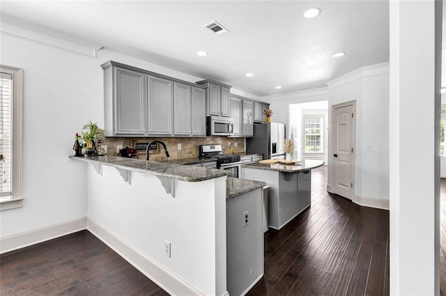 908 Rainsong Ct, Braselton, GA 30517 - kitchen with appliances with stainless steel finishes, a breakfast bar, gray cabinets, stone counters, and recessed lighting