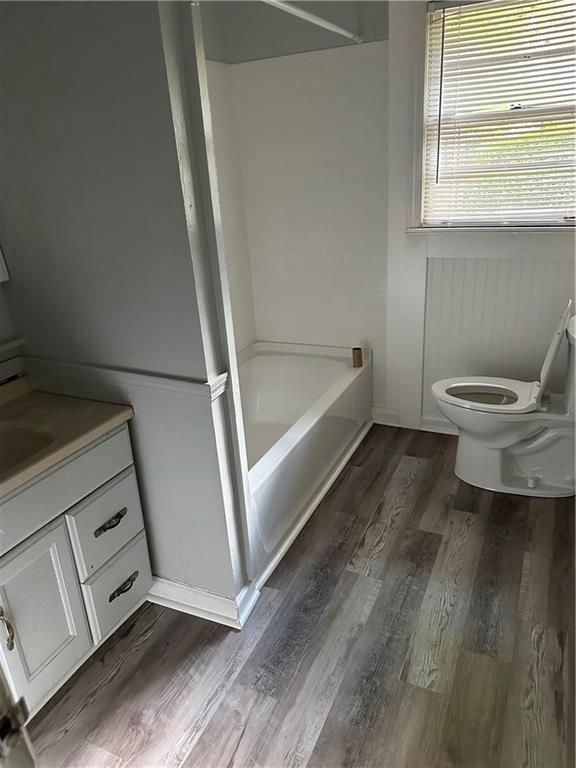 bathroom with toilet, wood finished floors, vanity, and bathtub / shower combination