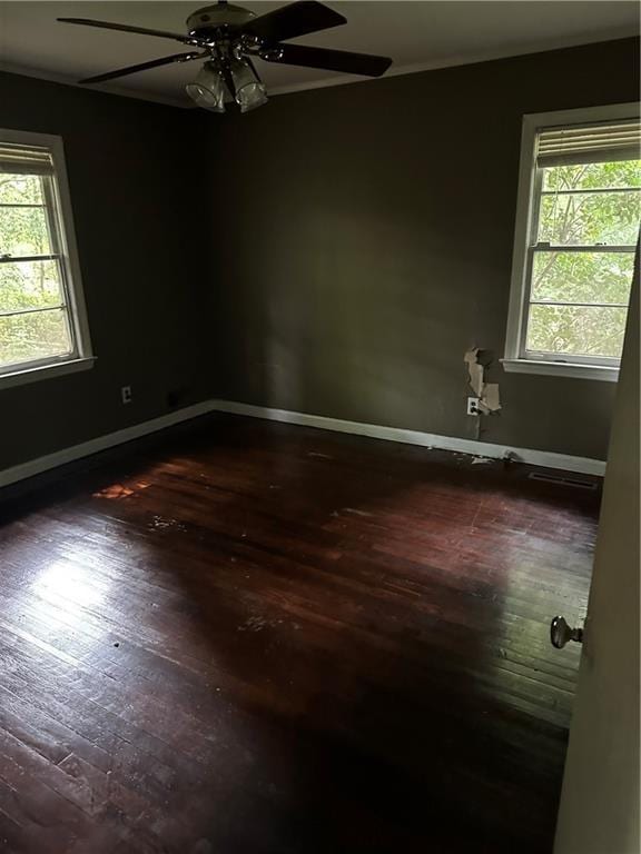 unfurnished room featuring dark wood finished floors, a ceiling fan, and healthy amount of natural light