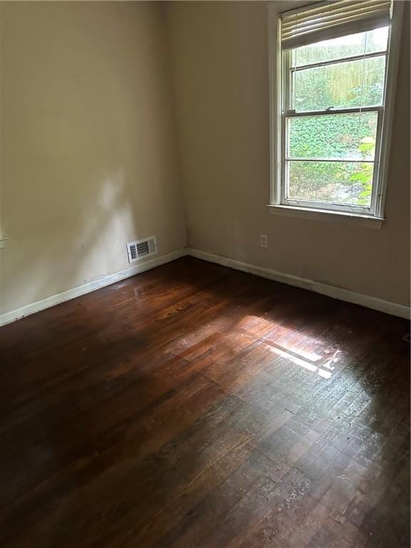 empty room with dark wood finished floors and baseboards