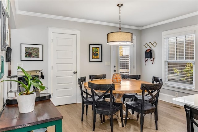 dining space with baseboards, crown molding, and light wood finished floors