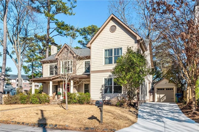 traditional home featuring a detached garage, a porch, an outdoor structure, concrete driveway, and a chimney