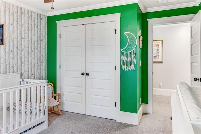 bedroom featuring baseboards, ornamental molding, carpet floors, a closet, and a nursery area