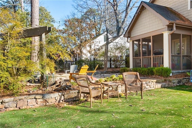 view of yard featuring fence, a sunroom, and an outdoor fire pit