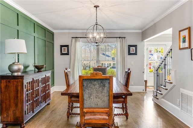 dining space with stairway, wood finished floors, visible vents, crown molding, and a chandelier