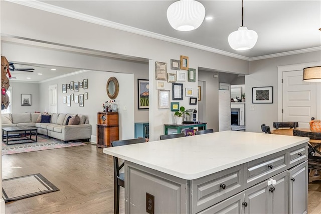 kitchen with light countertops, a fireplace, gray cabinets, and ornamental molding