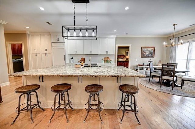 kitchen with paneled built in fridge, white cabinets, light hardwood / wood-style floors, and a large island