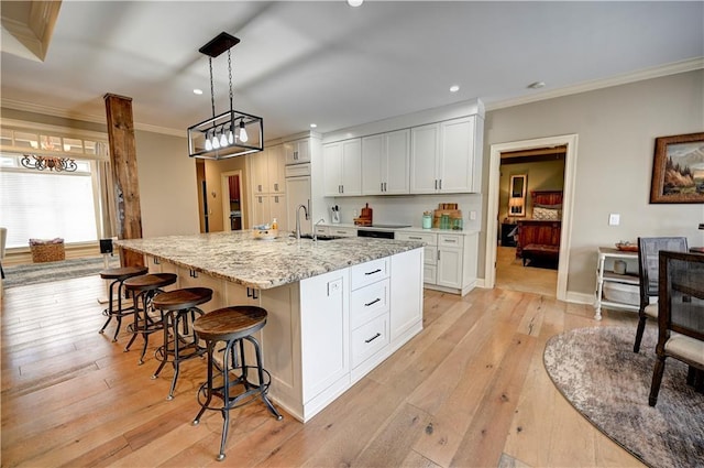 kitchen with a center island with sink, light hardwood / wood-style floors, and white cabinetry