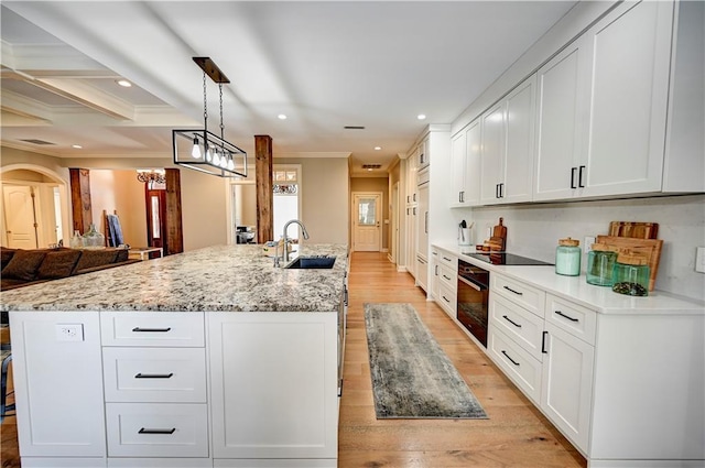 kitchen with sink, white cabinets, decorative light fixtures, and black appliances