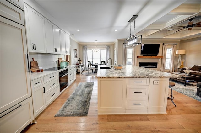 kitchen with a kitchen island with sink, white cabinets, and light hardwood / wood-style floors