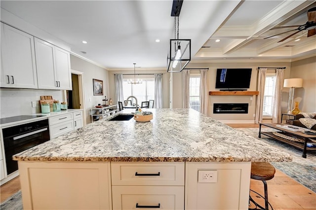 kitchen with a spacious island, sink, hanging light fixtures, and black appliances