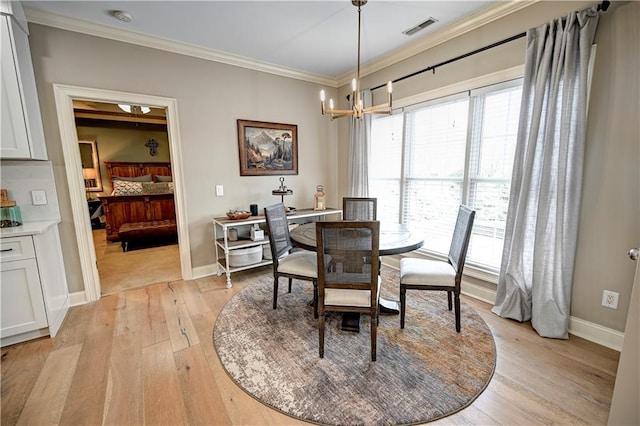 dining room with light wood-type flooring, ornamental molding, and an inviting chandelier