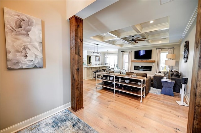 living room with coffered ceiling, crown molding, ceiling fan, beamed ceiling, and light hardwood / wood-style floors