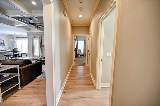 corridor with coffered ceiling, a chandelier, light hardwood / wood-style floors, ornamental molding, and beam ceiling