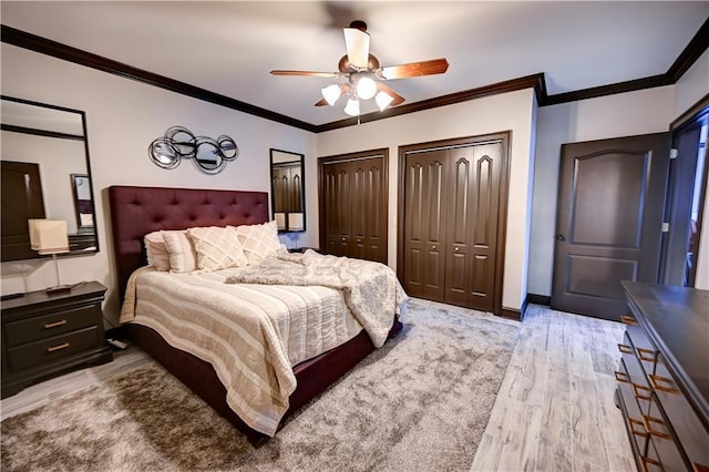 bedroom with ceiling fan, crown molding, light hardwood / wood-style floors, and multiple closets