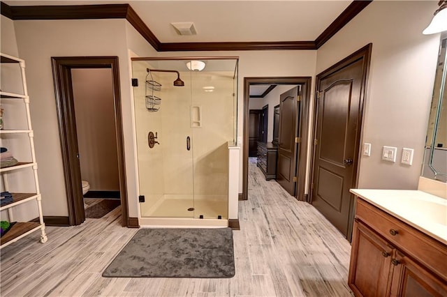 bathroom featuring a shower with door, ornamental molding, toilet, wood-type flooring, and vanity