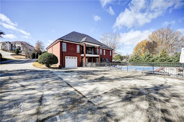 view of home's exterior with a community pool, a balcony, and a garage