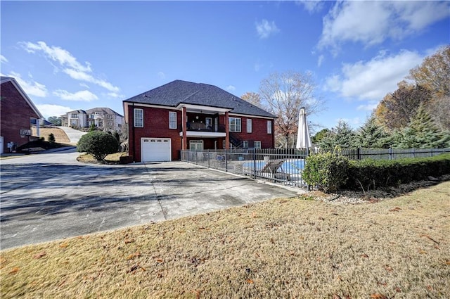 exterior space with a front yard, a balcony, a garage, and a community pool