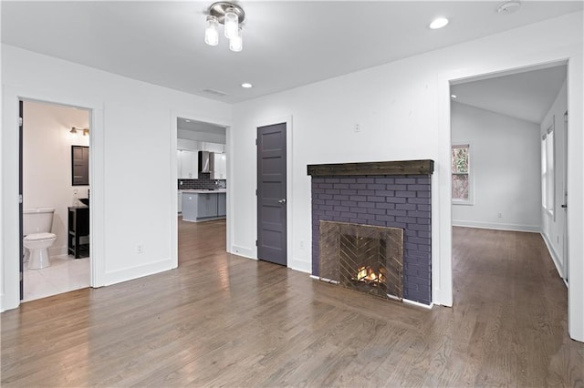 unfurnished living room with vaulted ceiling, dark wood-type flooring, and a fireplace