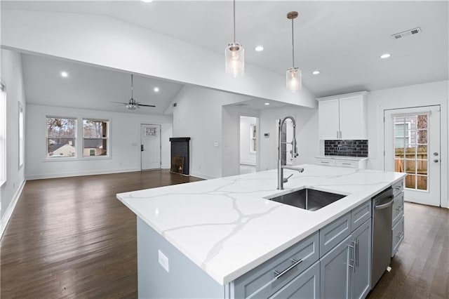 kitchen with vaulted ceiling, pendant lighting, dishwasher, sink, and a center island with sink