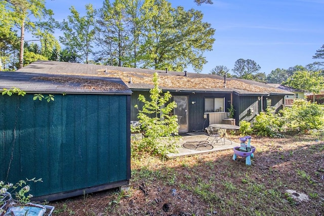 back of house with an outbuilding, a patio, and a storage shed
