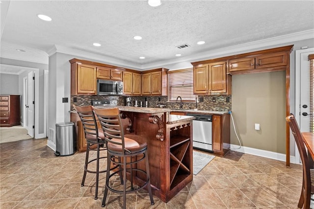 150 S St S, Buford, GA 30518 - kitchen featuring stainless steel appliances, a sink, crown molding, a kitchen island, and brown cabinets