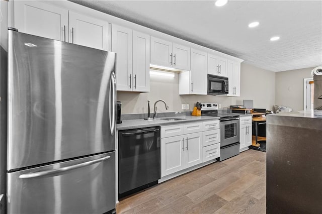 150 S St S, Buford, GA 30518 - kitchen with appliances with stainless steel finishes, a sink, recessed lighting, light wood-type flooring, and white cabinetry
