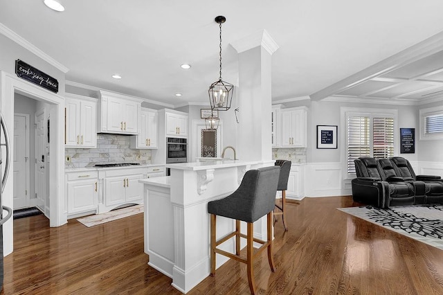 kitchen with decorative light fixtures, a kitchen breakfast bar, stainless steel oven, and white cabinets