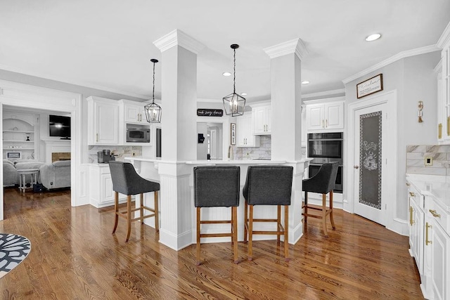 kitchen with pendant lighting, a breakfast bar area, white cabinetry, stainless steel appliances, and a kitchen island