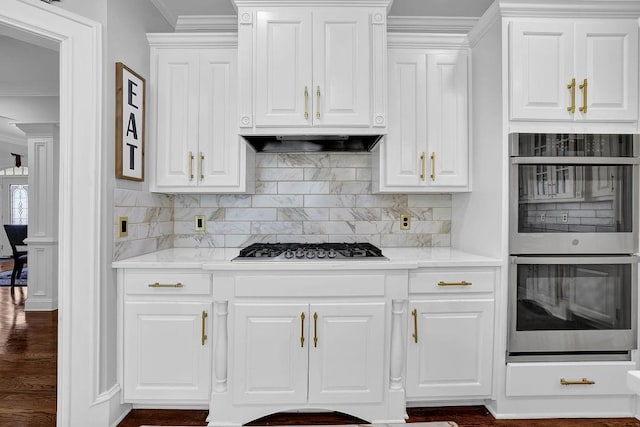 kitchen with light stone counters, ornamental molding, stainless steel appliances, decorative backsplash, and white cabinets