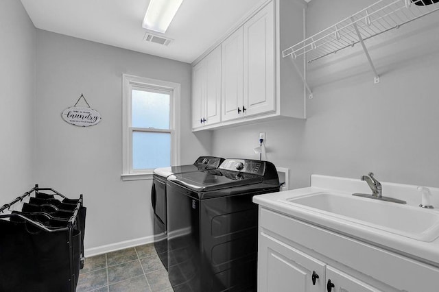 clothes washing area featuring cabinets, washing machine and dryer, sink, and dark tile patterned flooring